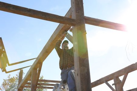 Bill Klein stands on a ladder and uses a mallet to take down beams from the old barn. (National Geographic)