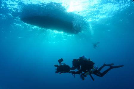 Crew Nuno Sa scuba dives with a camera underneath the boat. (National Geographic/James Loudon)
