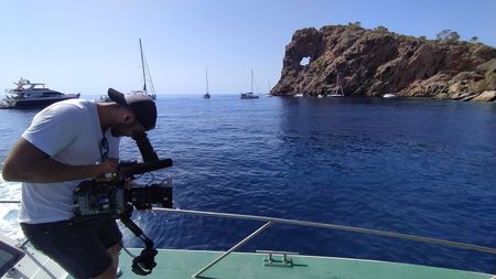 A camera operator records from the deck of a ship  in a behind-the-scenes image in Ibiza, Balearic Islands, Spain. (National Geographic/Salvador Antonio Díaz Montes)