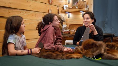 Sonta Roach teachers her daughters Sydney and Emry how to make mittens out of beaver fur. (BBC Studios/Brian Bitterfeld)