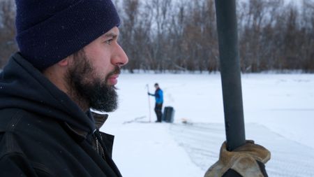 Chevie Roach teaches his son Ryder how to set a fish net under the ice. (BBC Studios/Brian Bitterfeld)