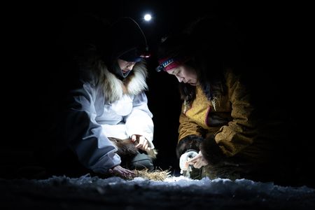 Agnes Hailstone and her daughter, Iriqtaq ice fish in the night on the river. (BBC Studios Reality Productions, LLC/Dwayne Fowler)