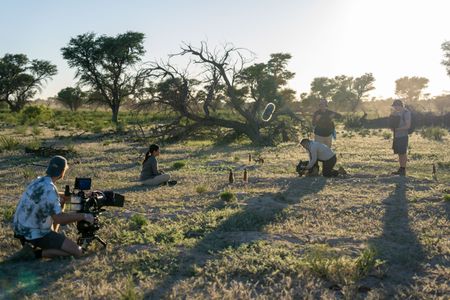 Crew film Liz Bonnin as she watches a meerkat gang emerge from their burrow at sunrise. (National Geographic/Emilie Ehrhardt)