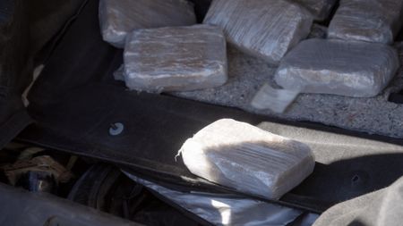 CBP Officer Gonzalez holds a package of suspected narcotics after extracting it from the tire of a suspect's vehicle. in El Paso, Texas. (National Geographic)