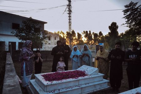 Amir Waseem, Tahira Perveen and other family members gather at the gravesite of Chaudry Wali Mohammad at his family home  in Rawalpindi, Pakistan. Corporal Chaudry Wali Mohammed was a member of Force K6, an Indian Regiment of mule handlers in WW2. Amidst the chaos of Dunkirk and the advancing German Army, one little-known Indian Regiment fights for victory and independence. (National Geographic/Daniel Dewsbury)