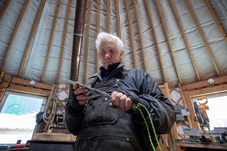 Andy Bassich creates a snow knife that will help him build a snow shelter for himself and his partner, Denise. (BBC Studios Reality Productions/Ben Mullin)