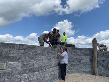 Tobias Edgett adds caulking, while Charles Pol, Carter Korthals, Kyle Knoche, Andrew Hutton, and Seth Doble stack cement blocks for the Pol family farm's sheep hut wall. (National Geographic)