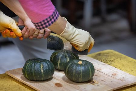 Yoon Hee Lee and Awkwafina cut into a squash while making tteok. (Credit: National Geographic/Seong Joon Cho)