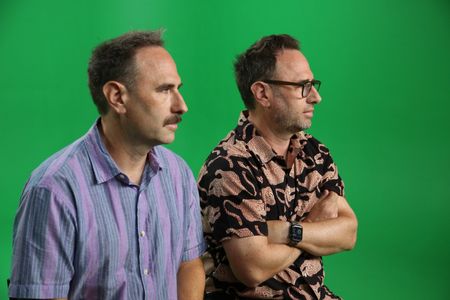 Randy and Jason Sklar sitting Infront of a green screen, listening to directions off camera. (National Geographic/Robert Toth)