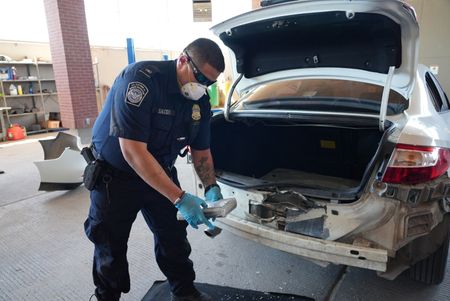 CBP Officer Salcido holds a package of suspected narcotics discovered smuggled in the rear bumper of a suspect's vehicle in El Paso, Texas. (National Geographic)