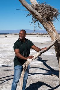 Christian Cooper examines the branch of a dead tree on the edge of the Salton Sea. (National Geographic/Jon Kroll)