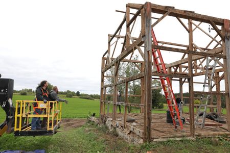 Charles Pol and Ben Reinhold, on a lift, look at the wooden framework left over from the old barn they are taking down. (National Geographic)