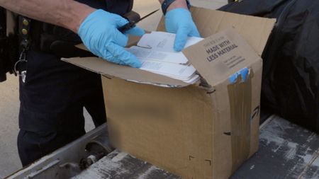 A CBP officer goes through a courier's packages to confirm their manifest in Dulles, Va. (National Geographic)