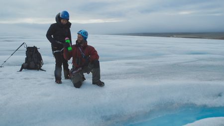 Melissa Marquez and glaciologist Andreas Alexander are on top of a glacier in Svalbard getting ready to deploy a 'drifter,' a piece of technology used to measure water temperature, speed, and depth of the glacial melt water. (National Geographic)