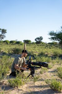 A meerkat uses cinematographer Adam Clarke as a vantage point to look out for predators. Meerkats at the Kalahari Research Centre are used to the presence of scientists, so see people as just another part of the landscape. (National Geographic/Emilie Ehrhardt)