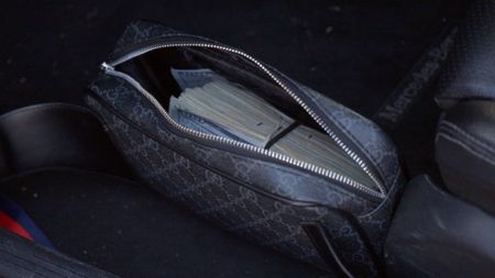 A Gucci bag filled with currency is pictured on the floor of a suspect's vehicle after it was found during an HSI operation in San Diego, Calif. (National Geographic)