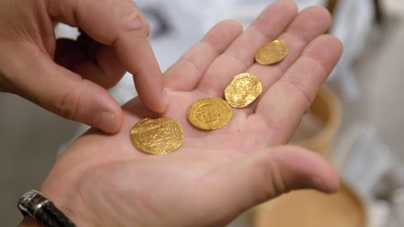 CBP Supervisory Officer Acevedo holds four gold coins on his hand after they were found in a shipment at the JFK International Airport in New York. (National Geographic)