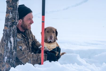 Johnny Rolfe and his dog Java collect ice glacial water by chipping clear ice blocks from the river. (BBC Studios Reality Production/Patrick Henderson)