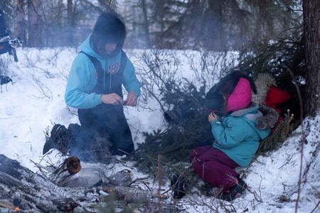 Ricko DeWilde cooks dinner over an open fire in the woods with his daughter, Maya DeWilde. (BBC Studios Reality Productions, LLC/Ryan Walsh)