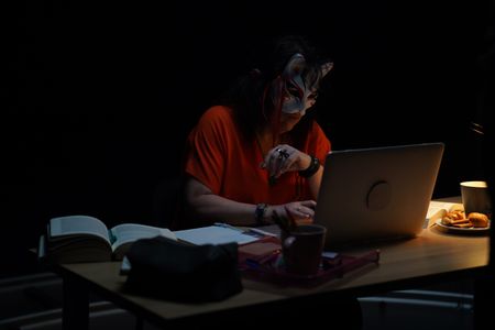 Member of the 4th Eye Corporation "Saturne" poses for a portrait while working at a desk for "Killer Lies: Chasing a True Crime Con Man," a documentary series about obsession and deception, following the unraveling of Stephane Bourgoin’s career as a best-selling author and serial killer expert. "Saturne" is a pseudonym; she chose to remain anonymous. (National Geographic/Ben Selkow)