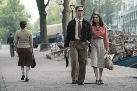 A SMALL LIGHT - Jan Gies, played by Joe Cole, and Miep Gies, played by Bel Powley, walk along the canal as seen in A SMALL LIGHT. (Credit: National Geographic for Disney/Dusan Martincek)