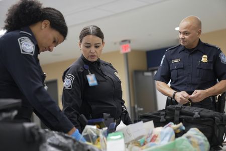 CBP Officers Evans, Laska and Supervisory Officer Pacheco talk while they go through a passenger's luggage in Atlanta, Ga. (National Geographic)