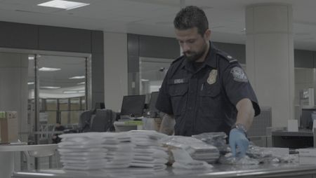 CBP Officer Hundal inspects multiple electronic devices found in a courier's belongings in Dulles, Va. (National Geographic)