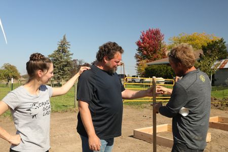 Beth Pol and Charles Pol listen to Ben Reinhold as he explains how to hold a shovel, in the Pol family farm's new garden. (National Geographic)