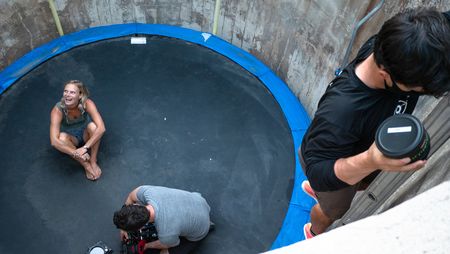 Angel Collinson sits on the trampoline as cinematographer Nick Kraus sets up the camera and assistant cameraperson Galen Murray climbs the ladder with a lens change.   (National Geographic/Elena Gaby)