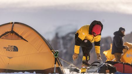 Alex Honnold places a tent peg into the snow as he pitches his tent on the Renland Icecap in Eastern Greenland.  (photo credit: National Geographic/Pablo Durana)