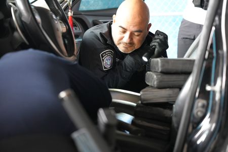 Multiple packages of suspected narcotics are sitting on the driver's seat of a suspect's vehicle while CBP Officers Torres and Ramirez continue to search for contraband in Brownsville, Texas. (National Geographic)