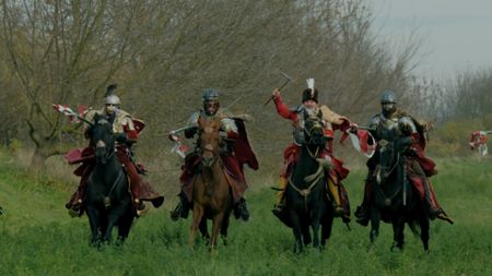 Soldiers cantering on horses waving weapons. (National Geographic)