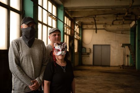 4th Eye Corporation members Sven, "Saturne" and "Valak" pose for a portrait in a warehouse. They are featured in "Killer Lies: Chasing a True Crime Con Man," a documentary series about obsession and deception, following the unraveling of  Stephane Bourgoin’s career as a best-selling author and serial killer expert. The 4th Eye Corporation is an online group of true crime fans which formed in 2019 to investigate the details of Stéphane Bourgoin’s life and career. "Saturne" and "Valak" are pseudonyms. (National Geographic/Ben Selkow)