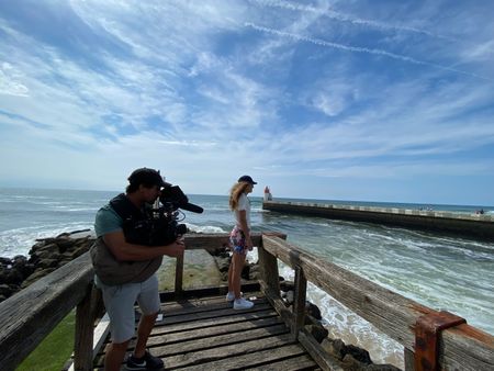 Facing the pier, right next to the water, big wave surfer Justine Dupont admires the sea, as DP Alfredo de Juan films her from behind.  (National Geographic/Gene Gallerano)