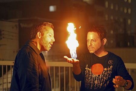 Cyril Takayama (wearing the David mask) demonstrates his fire hand trick for David Blaine. (credit: National Geographic/Dana Hayes)