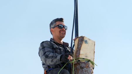 Joel Jacko installs a windmill on his property on a nearby tree. (National Geographic)