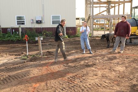 Ben Reinhold, Beth Pol, and Andrew Hutton discuss plans for the Pol family farm's new pond while the Pol family's dog, Atlas, watches. (National Geographic)