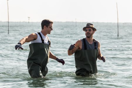 Antoni Porowski and Justin Theroux wade through the Po River. (National Geographic/Philippe Antonello)