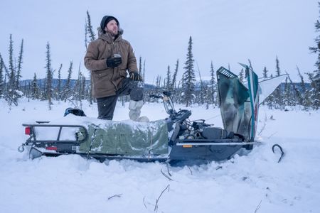 Johnny Rolfe fixes his snowmobile after it breaks down in the deep snow. (BBC Studios Reality Productions/Tyler Colgan