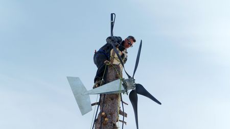 Joel Jacko installs a windmill on his property on a nearby tree. (National Geographic)