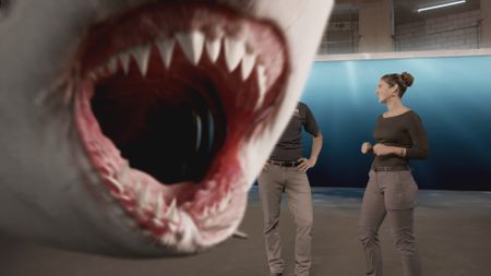 A GFX shark swimming across the studio lab screen as Dr. Mike Heithaus and Dr. Diva Amon discuss Tiger shark attacks. (National Geographic)