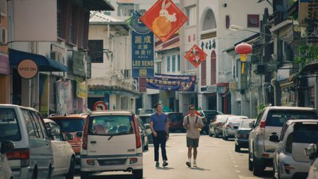 Henry Golding and Antoni Porowski walk down Carpenter Street in Kuching. (National Geographic)