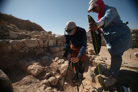 In this behind-the-scenes photo, crew member Andrew Richens and site worker Rasmi Khreashat take a close-up photo of the fresh find at the dig site in Jordan. (Windfall Films/Alex Collinge)