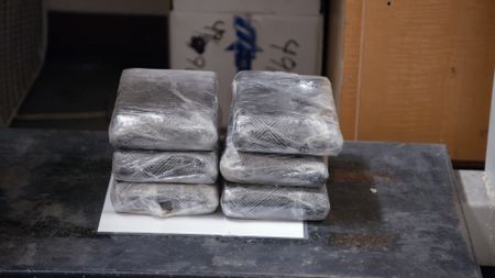 Multiple packages of cocaine found smuggled in the rear bumper of a suspect's vehicle are placed on a scale to be weighed in El Paso, Texas. (National Geographic)