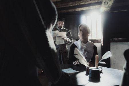 Geillis Duncan looks for remorse as David Seton continues to interrogate her. A member of the gentry is examining the documentation. (Dash Productions Services LTD/Antoan Ivanov)