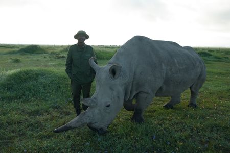 Head care giver, Zacharia standing next to a rhino. (Big Wave Productions)