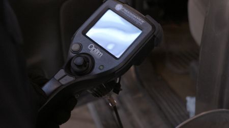 A CBP officer uses a video scope to better inspect the gas tank of a passenger's vehicle for hidden contraband in Calexico,  Calif. (National Geographic)