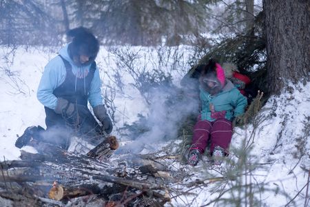 Ricko DeWilde cooks dinner over an open fire in the woods with his daughter, Maya DeWilde. (BBC Studios Reality Productions, LLC/Ryan Walsh)