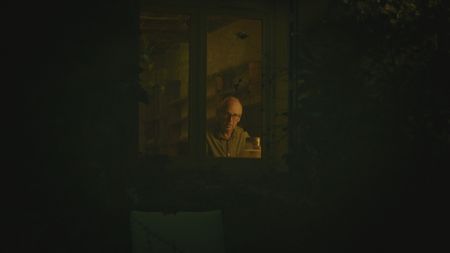 StÈphane Bourgoin is pictured through a window while he works at his desk during the production of "Killer Lies: Chasing a True Crime Con Man," a documentary series about obsession and deception, following the unraveling of  Stephane Bourgoinìs career as a best-selling author and serial killer expert. (National Geographic)