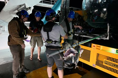 Eric Stackpole, Jorge Fontes, Colin Wollerman and Lee Frey adjust the harpoons and tags on the submarine at night. (National Geographic/Mario Tadinac)